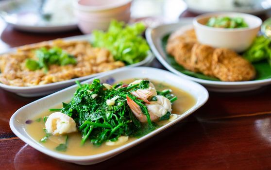 Stir-fried Vegetable fern with shrimp in white dish on wooden table