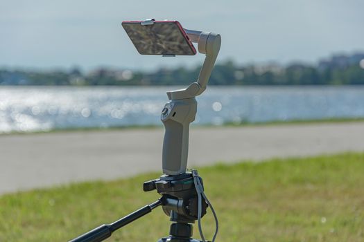smartphone is mounted on a studicam and mounted on a tripod, a blurry background with bokeh elements. Stock photo.