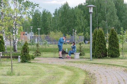 BELARUS, MINSK - MAY 27, 2021: A man and a woman have a picnic on a bench in a city park. Stock photography.
