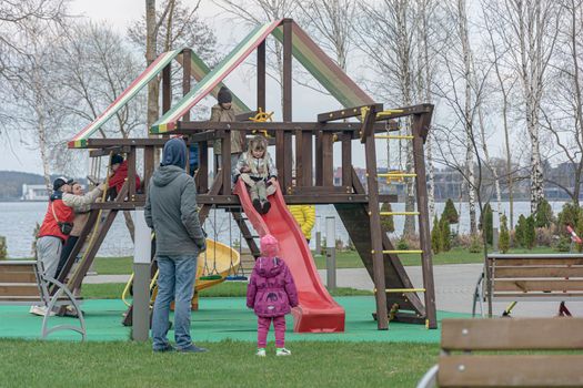 Belarus, Minsk - April 17, 2021: Parents with children without masks play in the playground and do not observe social distance. Stock photography.