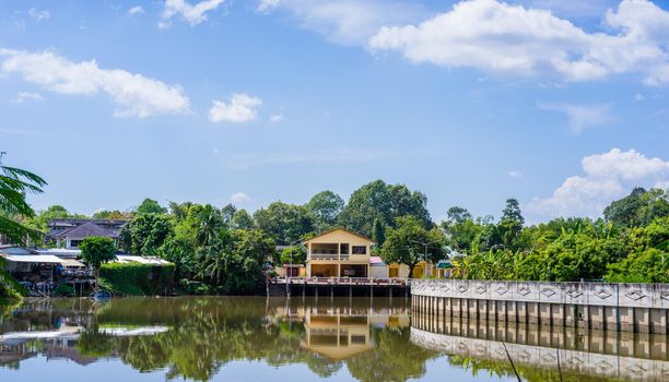 Riverside home and reflection on blue sky background