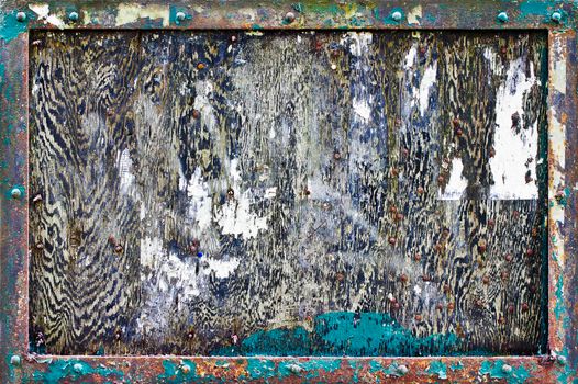 A heavily weathered and textured noticeboard to be used as a background. The noticeboard has a wooden back and metal frame.