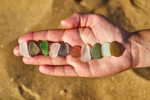 A person holds the sea glass they collected from a beach to show the different colours.