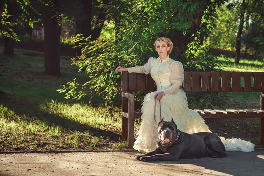 Girl in an old dress with ruffles and a big dark dog