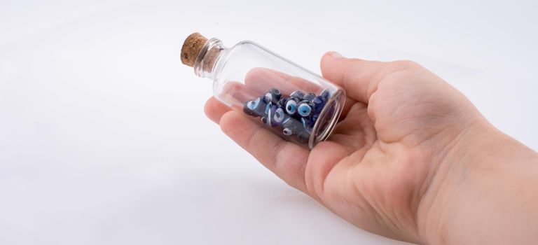 Little  glass bottle  with blue evil eye bead in hand