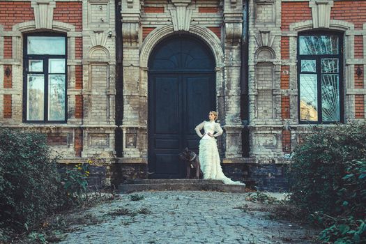 Girl in an old dress with ruffles and a big dark dog