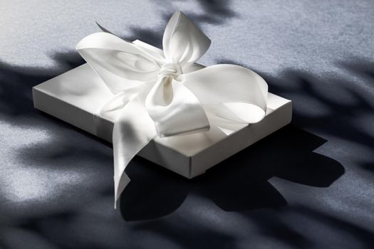 Anniversary celebration, shop sale promotion and luxe surprise concept - Luxury holiday white gift box with silk ribbon and bow on black background, luxe wedding or birthday present