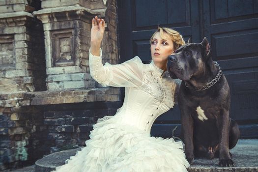 Girl in an old dress with ruffles and a big dark dog