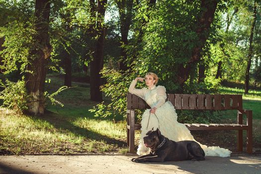 Girl in an old dress with ruffles and a big dark dog