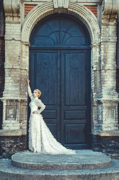 Blonde girl in a retro dress on the background of the old dark door of the building