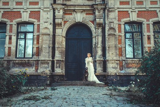 Girl in an old dress with ruffles and a big dark dog