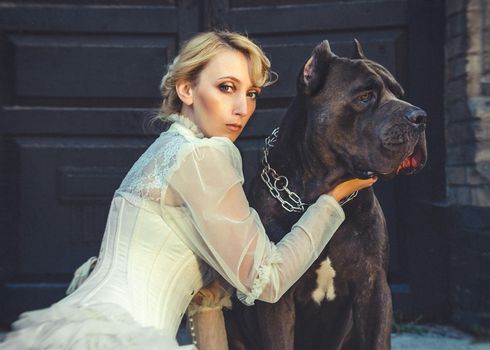 Girl in an old dress with ruffles and a big dark dog