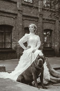 Girl in an old dress with ruffles and a big dark dog