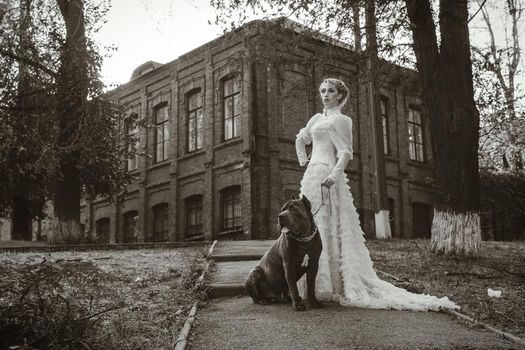 Girl in an old dress with ruffles and a big dark dog