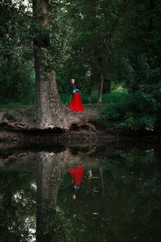 Girl model with white hair in a retro dress with ruffles in a green park