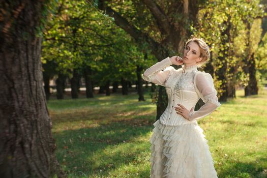 Girl model with white hair in a retro dress with ruffles in a green park