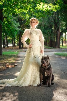 Girl in an old dress with ruffles and a big dark dog