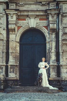 Girl in an old dress with ruffles and a big dark dog