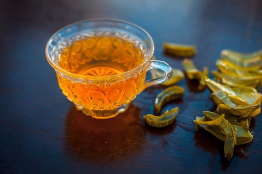 Hot herbal ayurvedic aloe vera tea on wooden surface in transparent glass cup with entire ingredients with it.Used to build immnue system, To Lower cholesterol levels and many more.