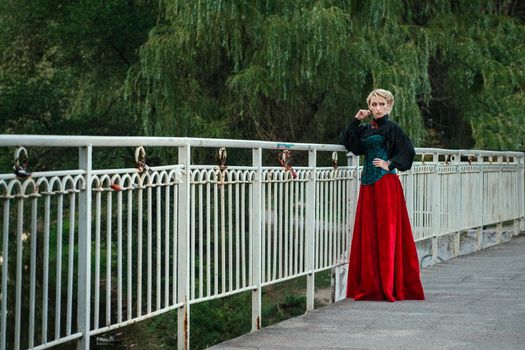 Girl model with white hair in a retro dress with ruffles in a green park