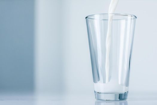 Dairy, healthy nutrition and breakfast concept - World Milk Day, pouring into glass on marble table