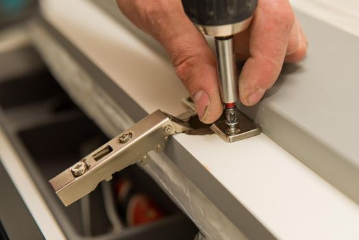 Fixing of the cabinet door hinge. Selective focus. Close up.