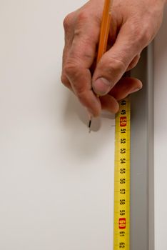 Close up of carpenter hands marks the furniture with a tape measure and a pencil.