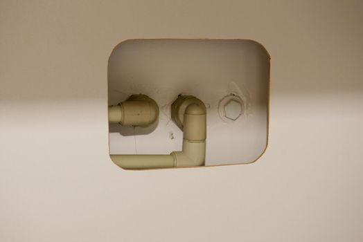 Hole in furniture for plastic water pipes in an apartment. Close-up.