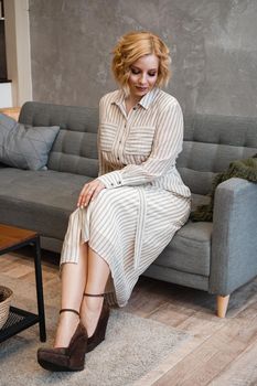 Woman with short blonde hair on sofa in light home room - vertical photo