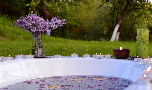 Romantic background with lilacs flowers and orange slices in a bathtub outdoor