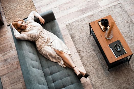 Top view of a smiling young woman relaxing on sofa at weekend an home