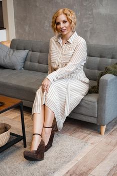 Woman with short blonde hair on sofa in light home room - vertical photo