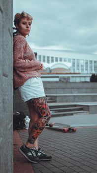 Beautiful young girl with tattoos with longboard in the town. She has traditional japanese tattoo