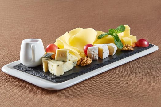 In the name of cheese. Closeup shot of a various sorts of cheese served on a plate with walnuts grapes and cranberries jam