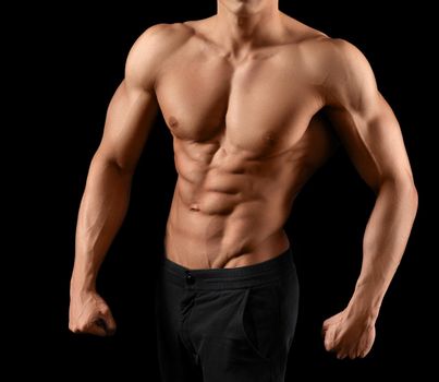 He puts a lot of work in this body. Cropped shot of a stunning hot torso of a male athlete posing on dark background