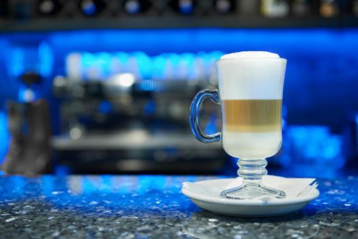 Coffemania. Shot of a glass cup full of coffee with milk coffee machine on the background copyspace