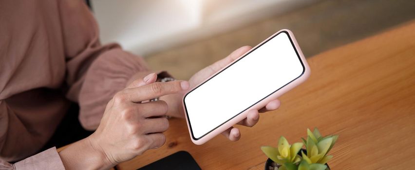 woman sitting and holding blank screen mock up mobile phone.