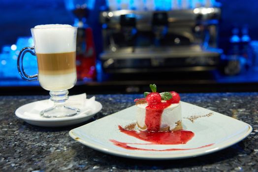 Enjoy the dessert. Closeup of a fresh tasty cheesecake decorated with cherries on top glass cup of coffee with milk on the background copyspace