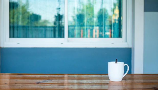 coffee cup on wooden table with window background