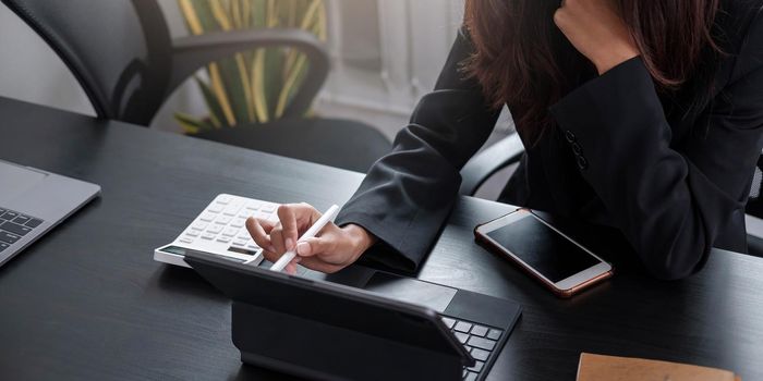 Business woman using calculator for do math finance on wooden desk in office and business working background, tax, accounting, statistics and analytic research concept.