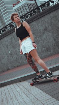 Beautiful young girl with tattoos with longboard in the town. She has traditional japanese tattoo