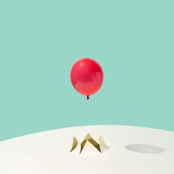 Red summer party balloon flying out of a crack on yellow and blue background. Minimal abstract concept. Square layout with copy space.