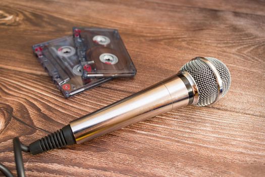 A silver-colored musical analog microphone rests next to old magnetic audio cassettes
