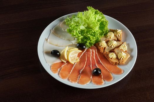 Yum yum. Top view of a smokes salmon served with lemon and salad leaves