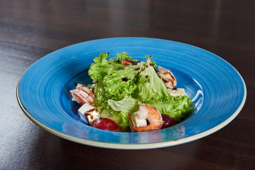Gotta love the shrimps. Closeup shot of a blue rustic plate full of fresh delicious shrimp salad