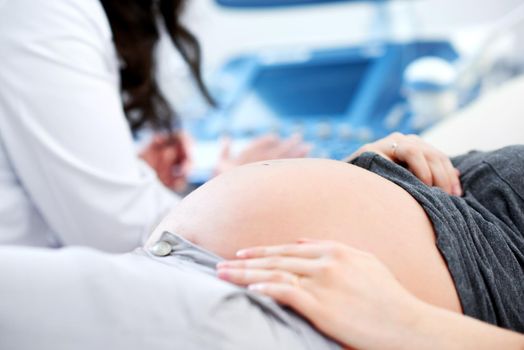 Cropped close up of a pregnant woman waiting for her doctor to start ultrasound scanning procedure at the hospital copyspace pregnancy expecting mother children healthcare family gynecology diagnosis.