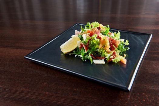 Healthy choice. Closeup shot of a summer salad with arugula green salad leaves and prosciutto spiced with lemon