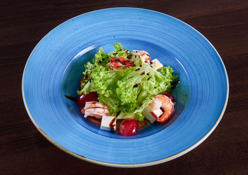 Meal is served. Fantastic delicious shrimp salad with feta cheese and grapes served in a big blue rustic plate top view