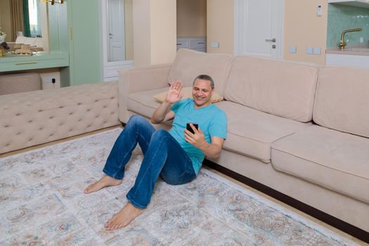 An adult man on the phone talking on video in an apartment.