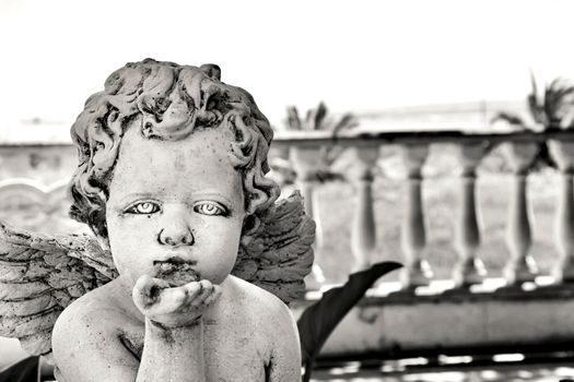 Elche, Alicante, Spain- July 3,2021: Beautiful angel sending a kiss made of white stone in a garden in Spain